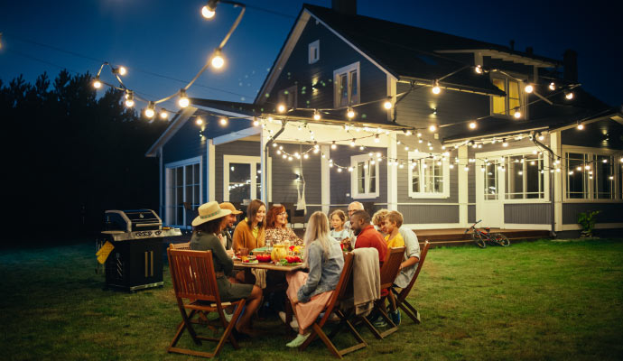 Outdoor dinner gathering by a lit house