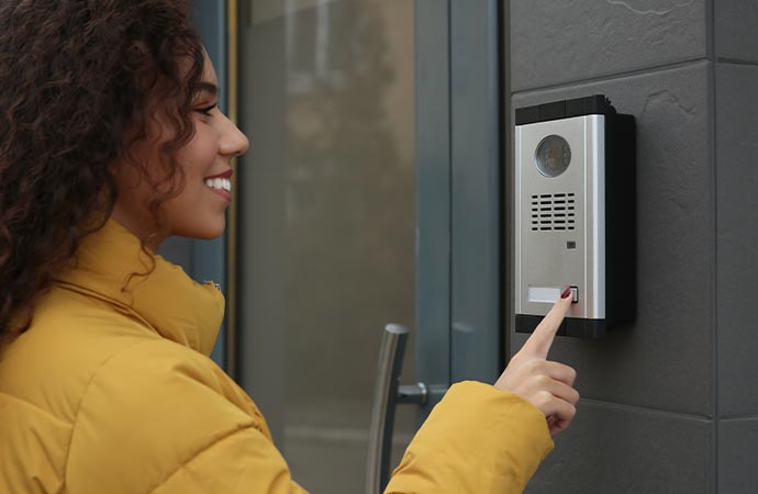 a woman is interacting with a wall mounted intercom system